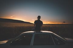 Boy Sitting On Top Of Car Watching Nature View