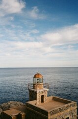 A light house sitting on top of a stone next to the ocean ...