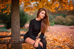 Woman sitting on a wooden bench under a tree ...