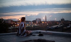 Girl Sitting On Rooftop Looking Towards Town